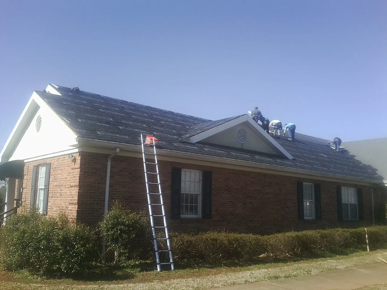 Crew tearing shingles off a brick ranch roof with a ladder set — Metal Roof Repair work by our crew in Santa Clara