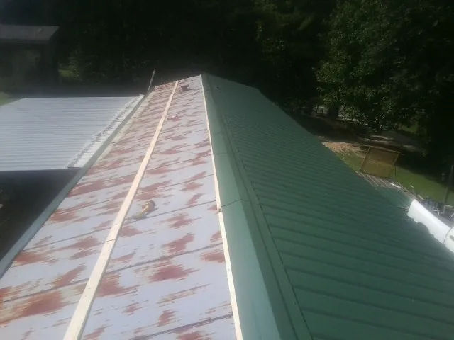 Old rusted panels beside newly installed green metal roofing — Wind Damage Roof Repair by Roofing Brothers in Santa Clara