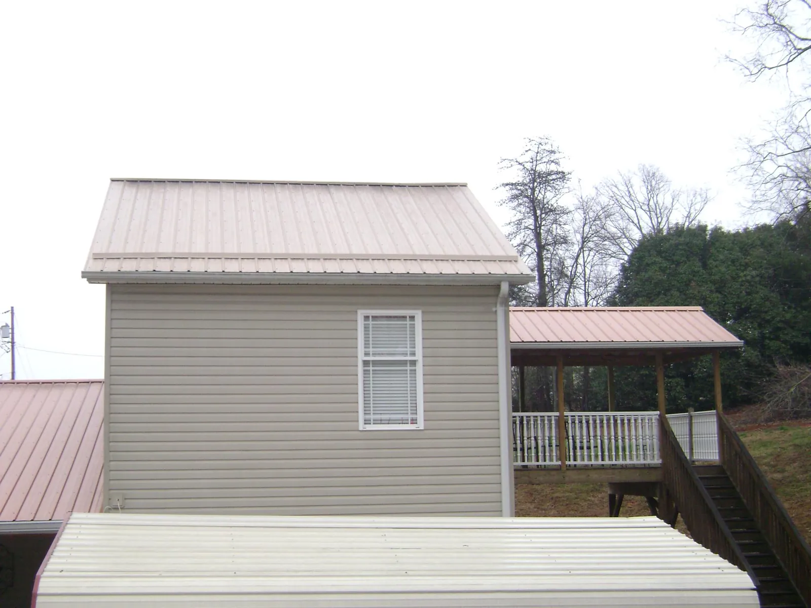 Tan metal roofs on a two story addition and attached porch, from a Roof Replacement job in Santa Clara