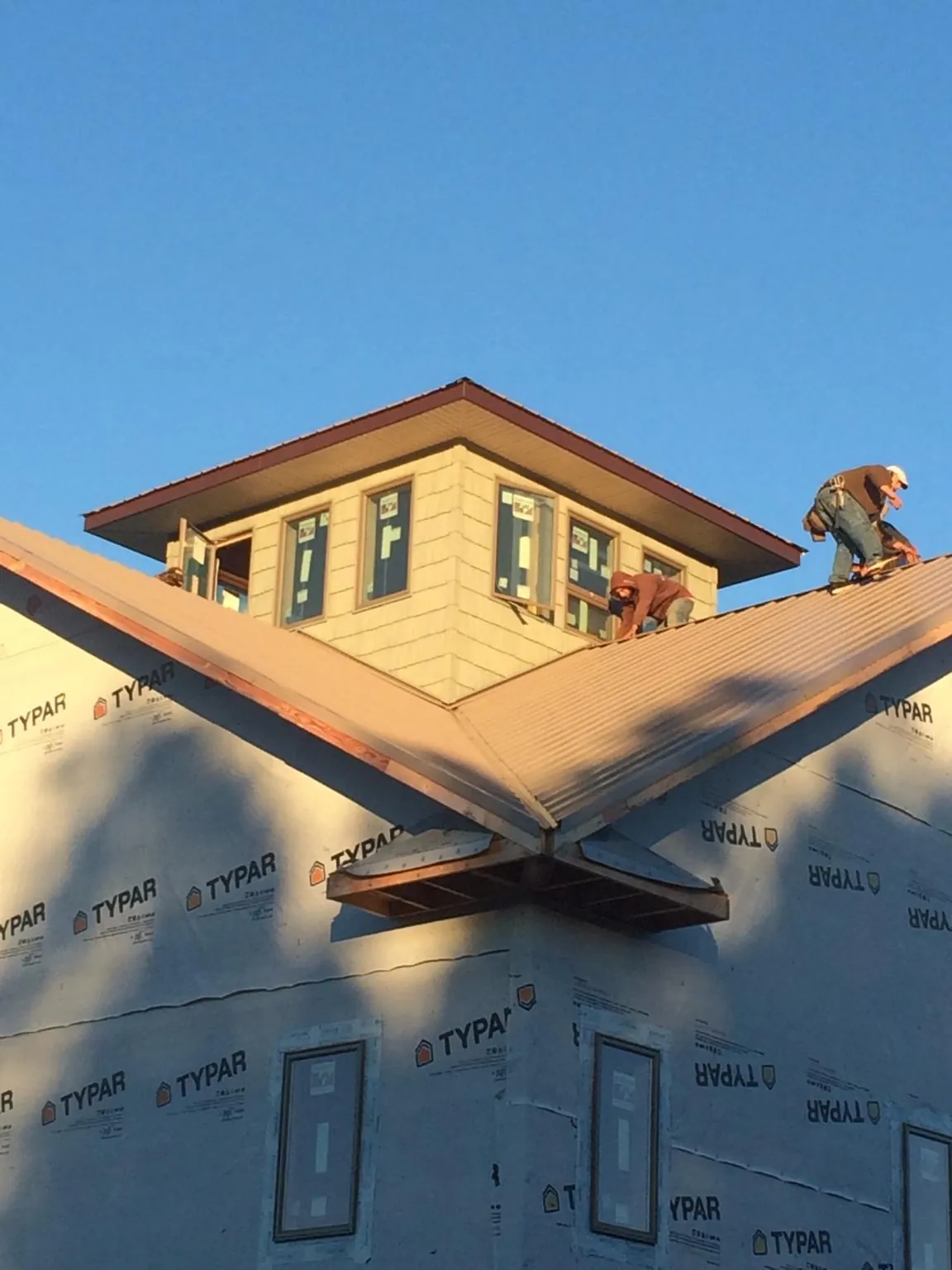 Roofers working around a rooftop cupola on a new metal roof at sunset — Roof Waterproofing in Santa Clara by Roofing Brothers